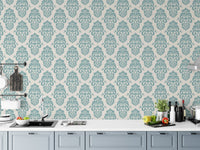 Teal and white damask wallpaper in a modern kitchen behind white cabinets.