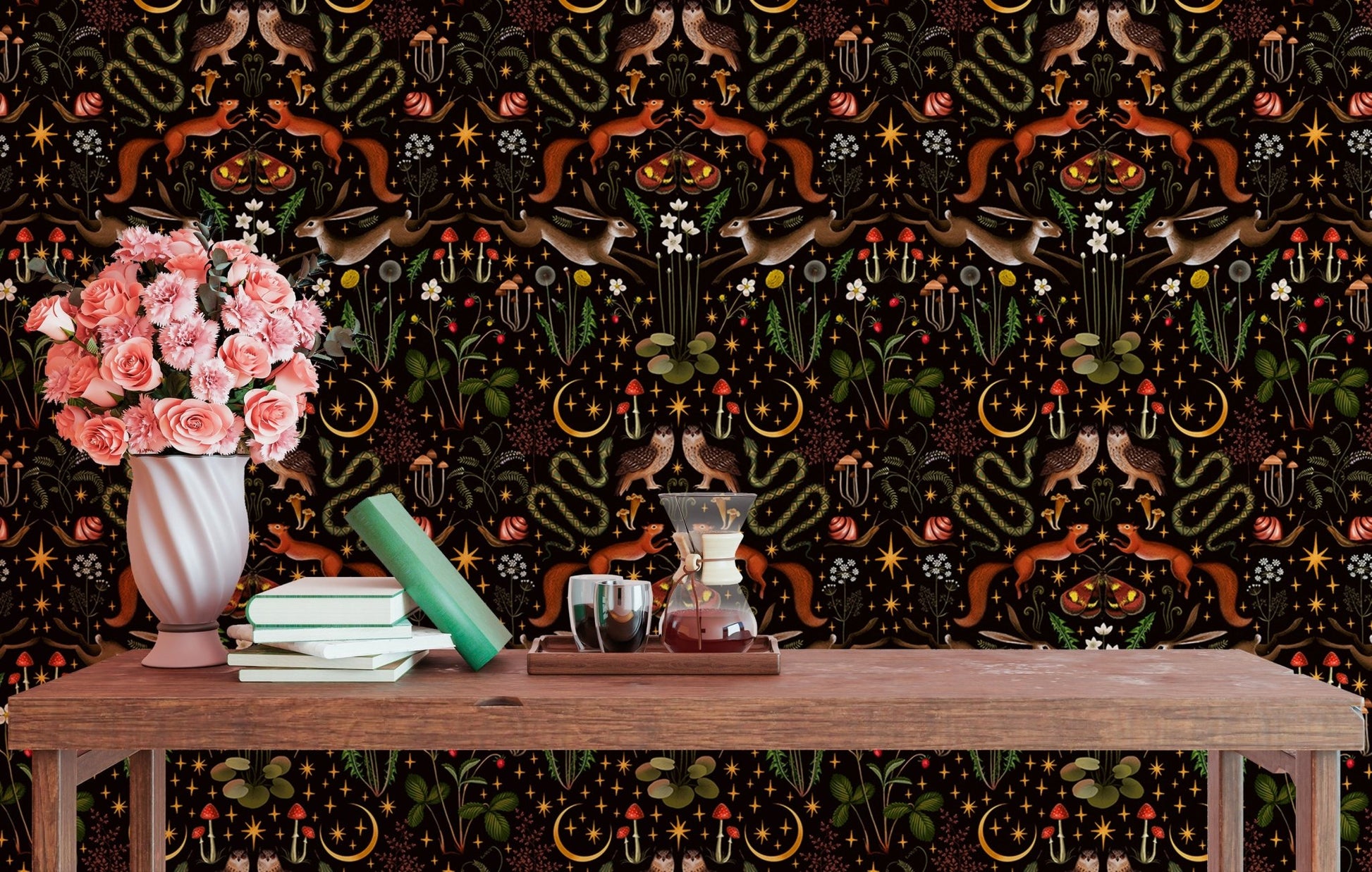 Dark forest themed wallpaper behind a wooden study table with books and a vase.