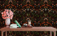 Dark forest themed wallpaper behind a wooden study table with books and a vase.