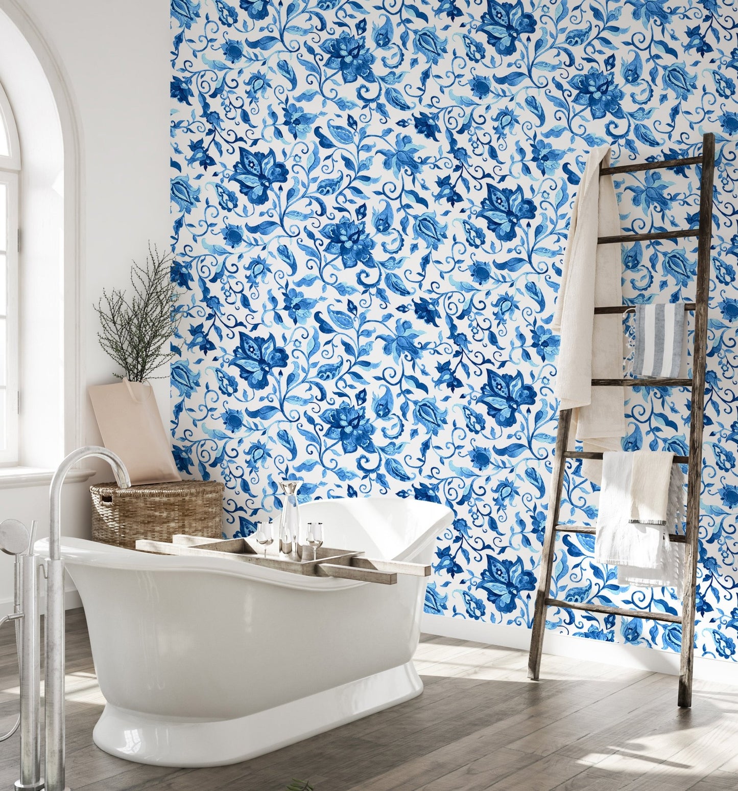 Bathroom wallpaper with blue botanical pattern and white freestanding bathtub.
