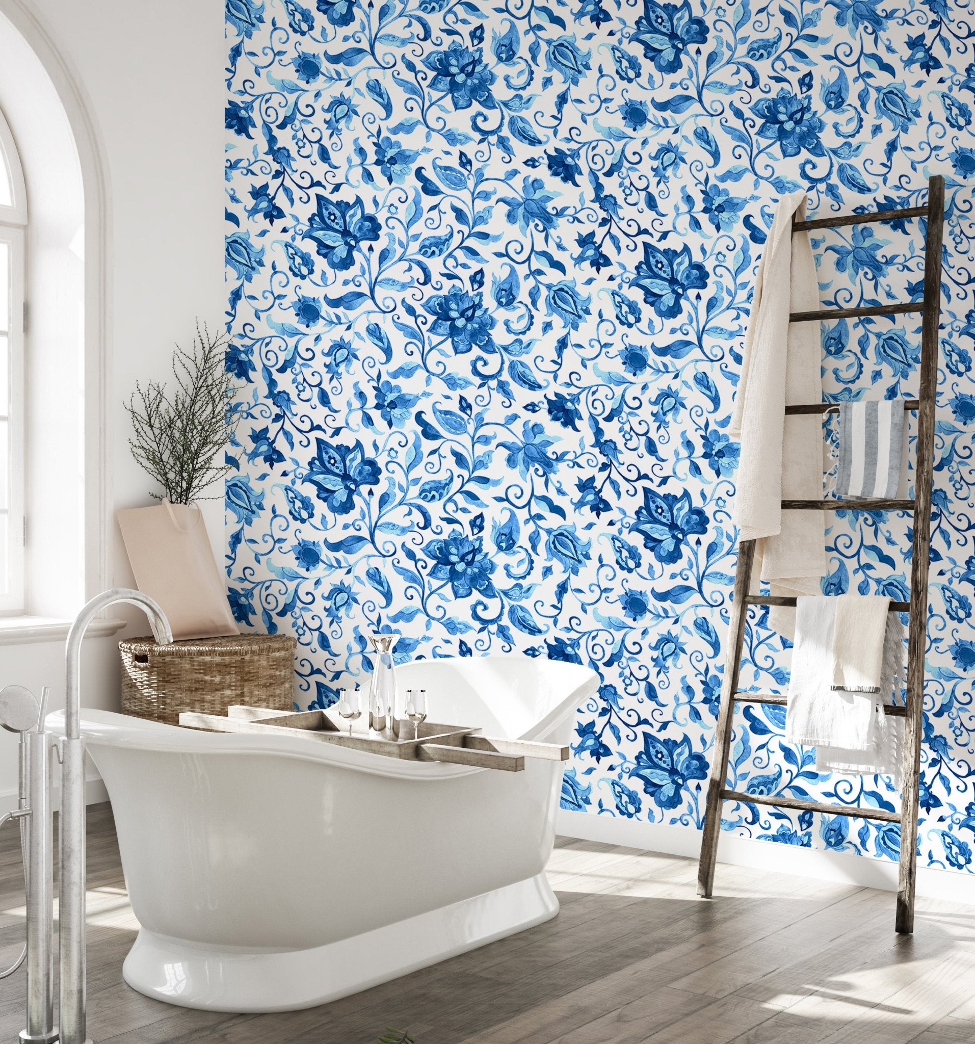 Bathroom wallpaper with blue botanical pattern and white freestanding bathtub.