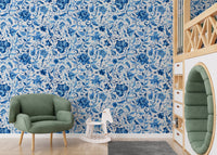 Green velvet chair in a room with blue watercolor floral wallpaper.