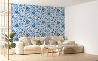 Large living room wallpaper with blue floral pattern behind a beige sofa.