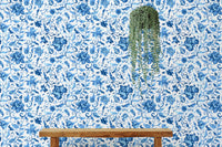 Hanging plant against blue paisley floral pattern wallpaper section.