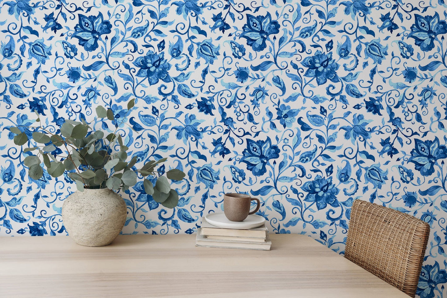 Home office wallpaper with blue flowers and leaves behind a wooden desk.