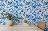 Home office wallpaper with blue flowers and leaves behind a wooden desk.