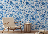 Mid-century armchair placed against blue watercolor floral wallpaper.