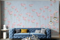 Soft pink floral wall mural on a textured light blue background surface.