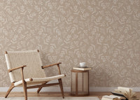 Pastel leaf wallpaper behind a lounge chair and wooden side table.