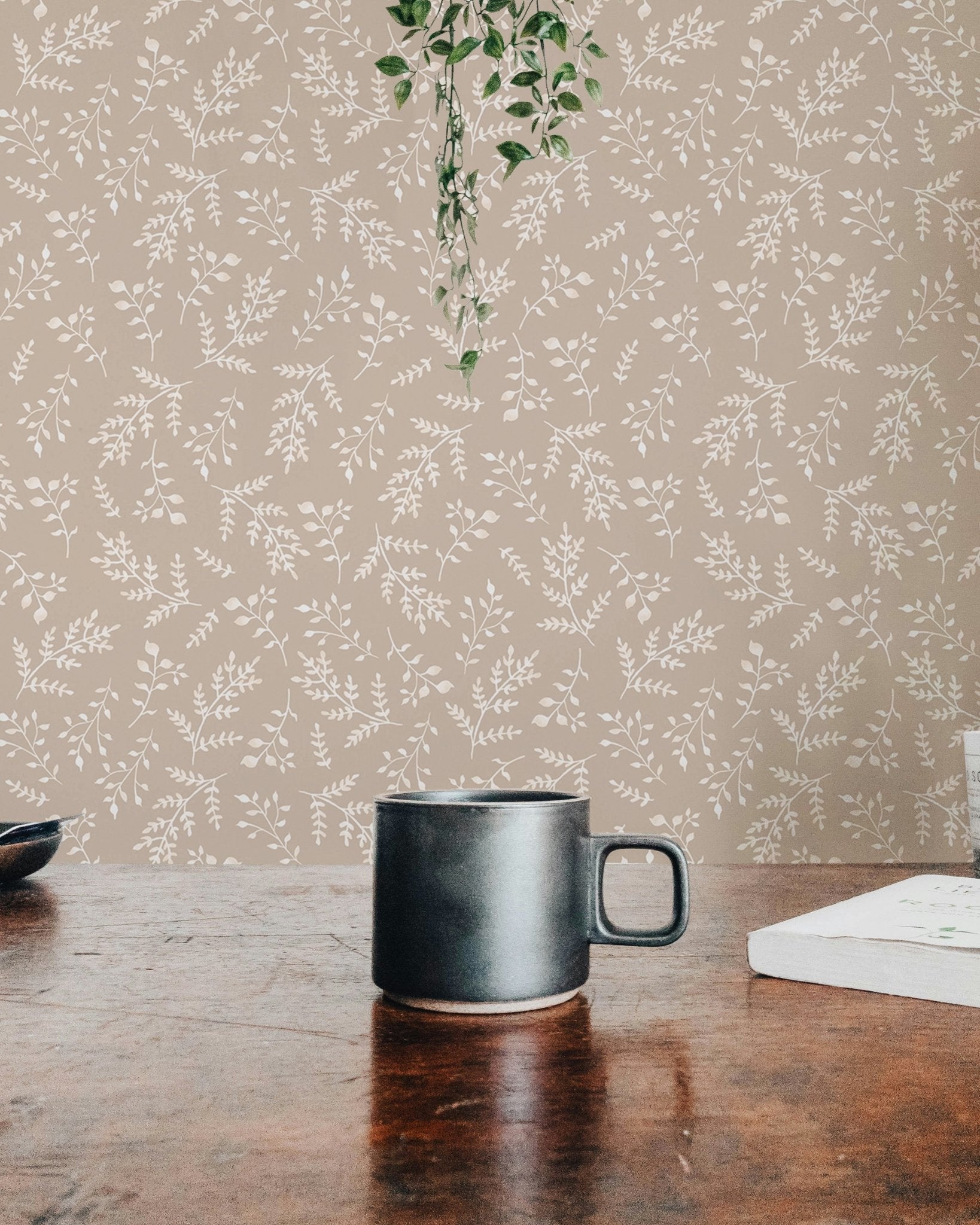 Detailed view of pastel foliage wallpaper behind a dark coffee mug.