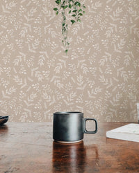 Detailed view of pastel foliage wallpaper behind a dark coffee mug.