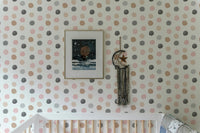 Grey and tan polka dot wallpaper in a minimalist nursery setting