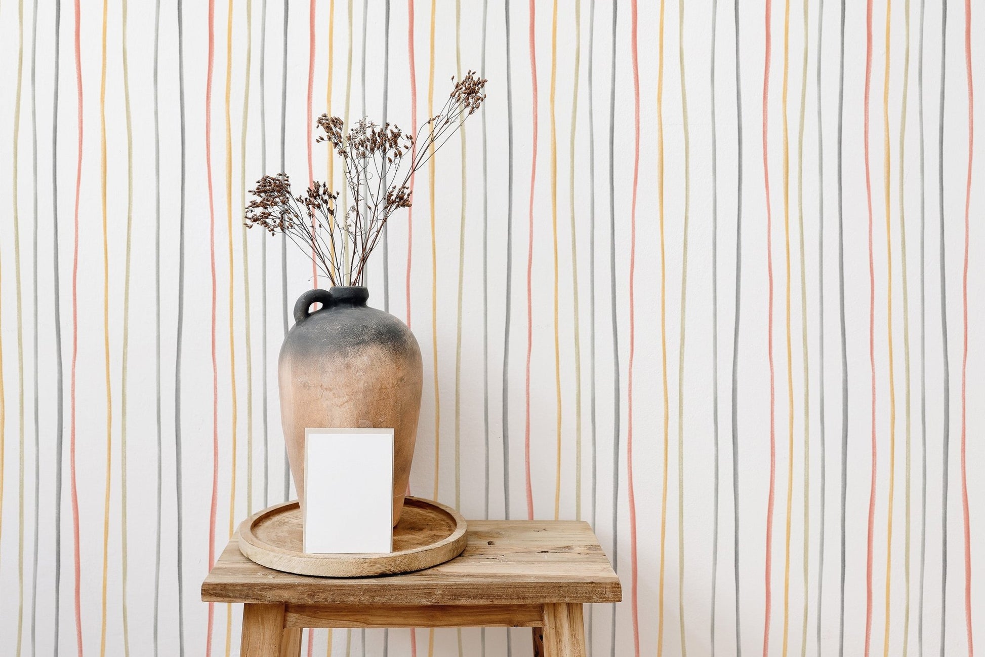 Hand drawn striped wallpaper behind a small table with a vase