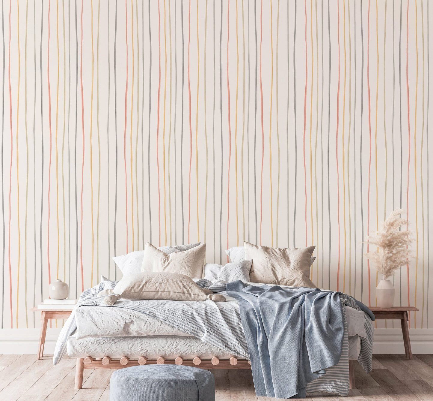 Hand drawn vertical stripes wallpaper behind a bed with blue blankets