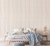 Hand drawn vertical stripes wallpaper behind a bed with blue blankets