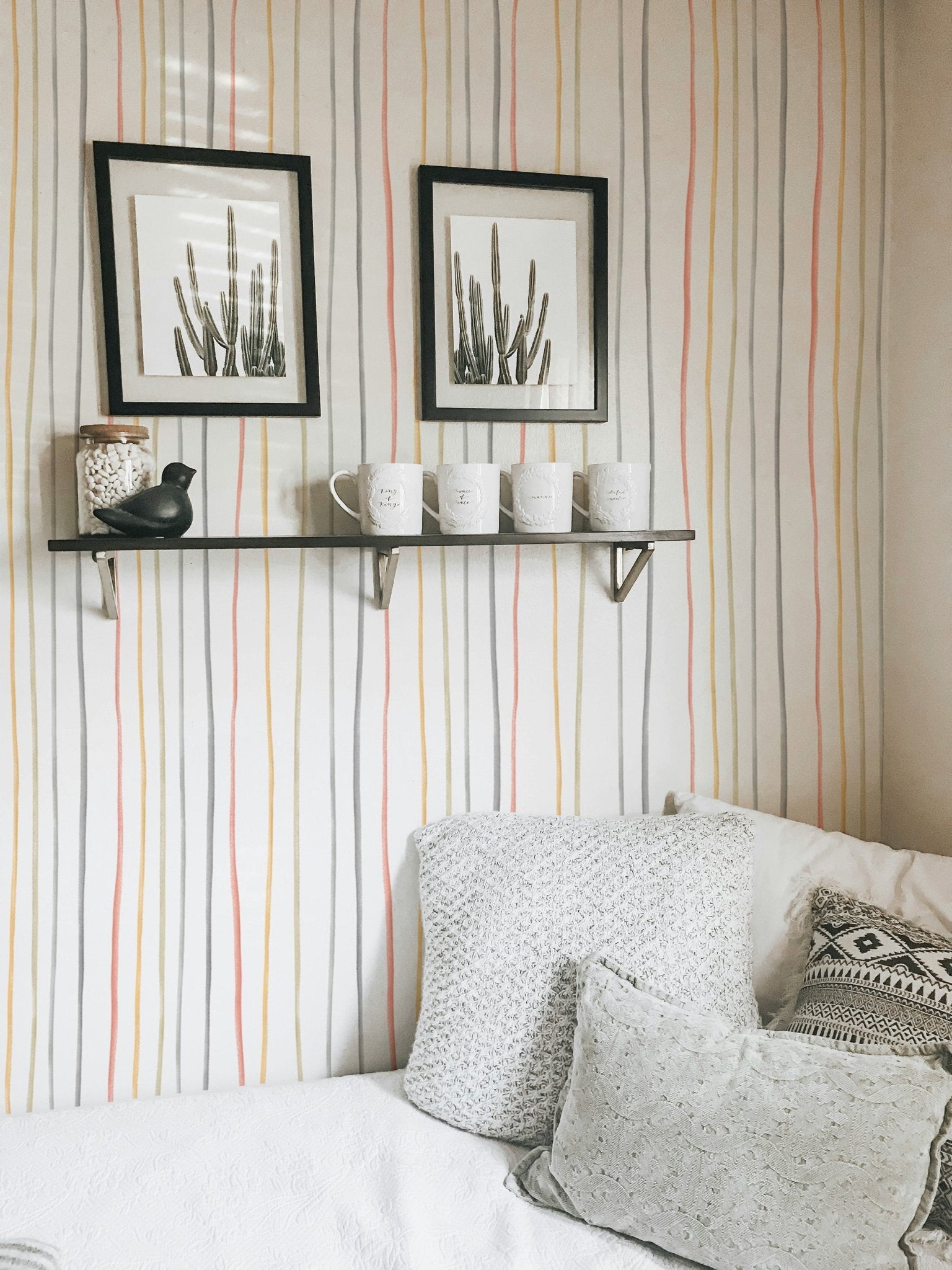 Striped pastel wallpaper behind a corner sofa and wall shelves
