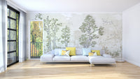 Muted green tree wall mural behind a white sectional sofa in a bright living area.