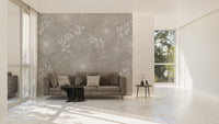 Grey flower wall mural behind a brown leather sofa in a bright living room.