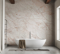 Symmetrical bathroom view with pink marble wall mural behind a white tub.