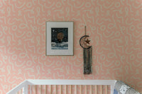 Abstract line wallpaper in a nursery above a wooden cot and framed art.