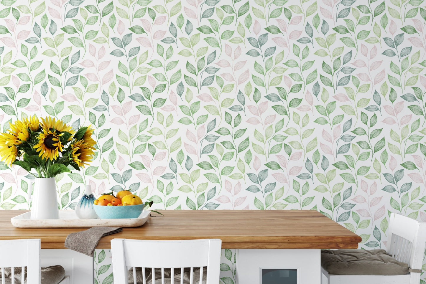 White dining chairs and table set against a leafy wallpaper with yellow flowers in dining area.