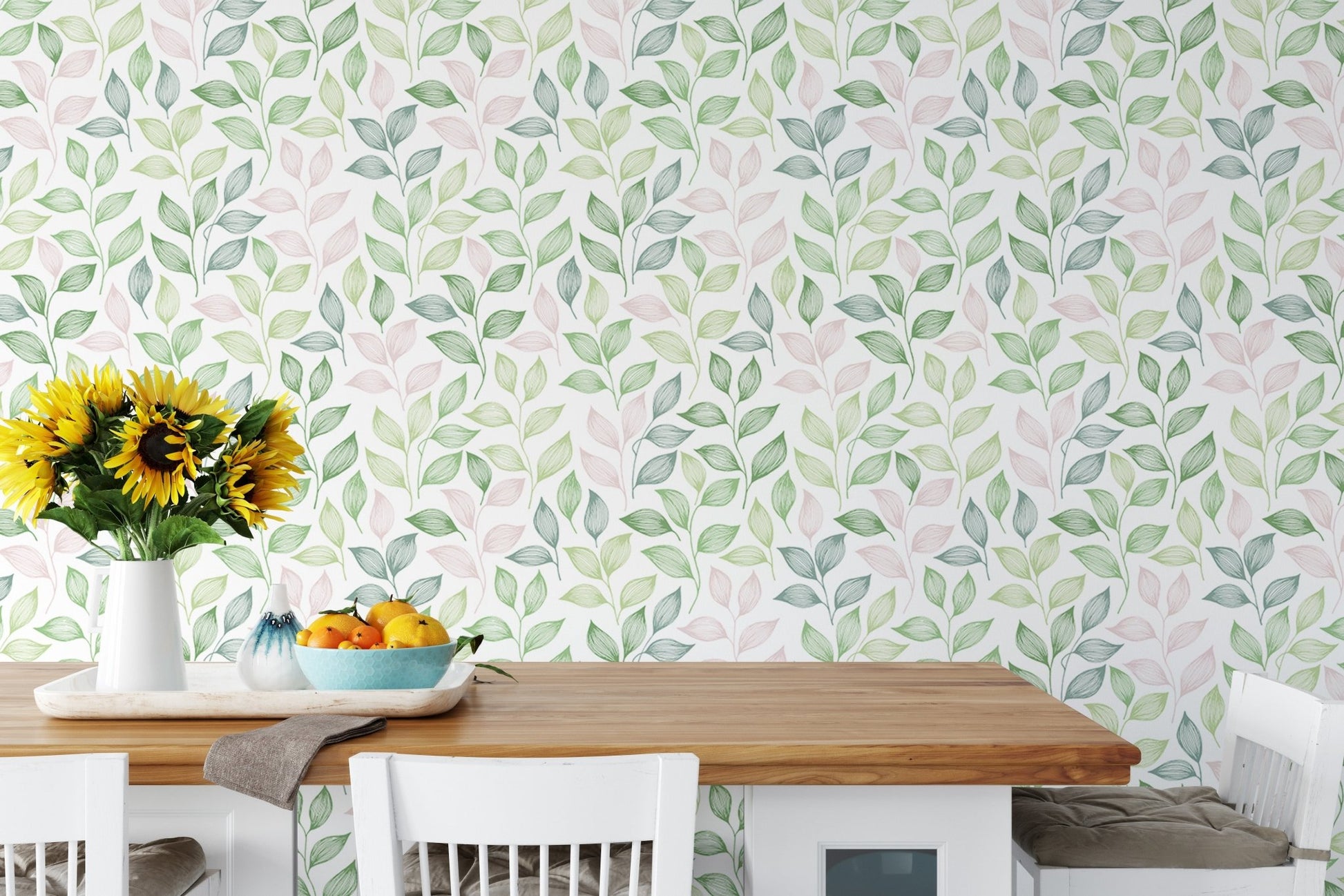 White dining chairs and table set against a leafy wallpaper with yellow flowers in dining area.