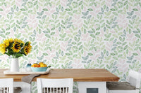 White dining chairs and table set against a leafy wallpaper with yellow flowers in dining area.