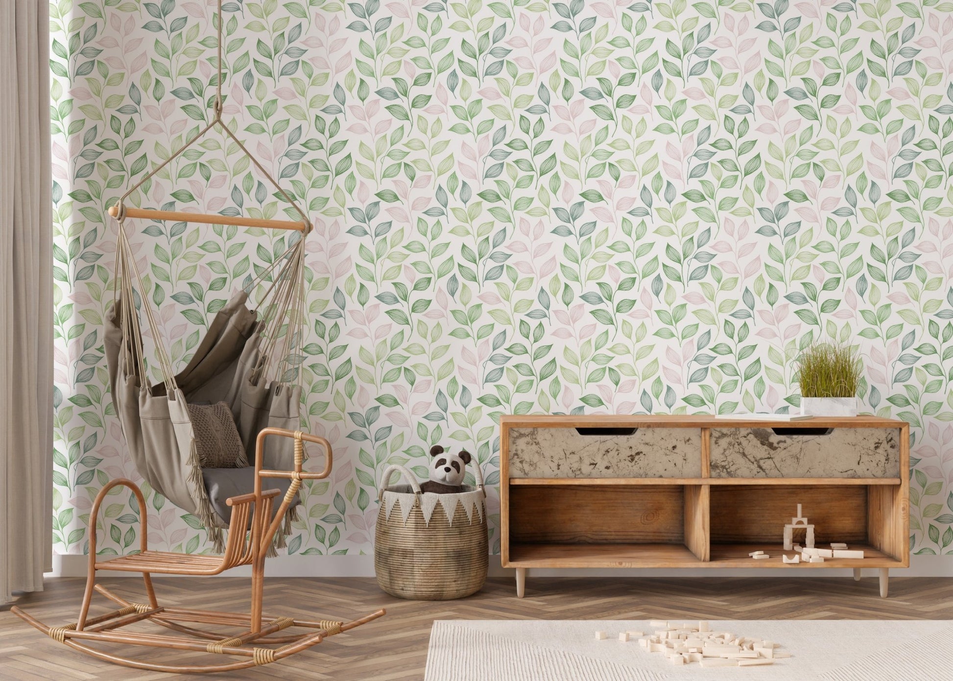Green Wallpaper with botanical motifs behind a wooden console and a hanging wicker chair.