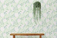 Hanging plant against a white wallpaper with green and pink botanical prints.