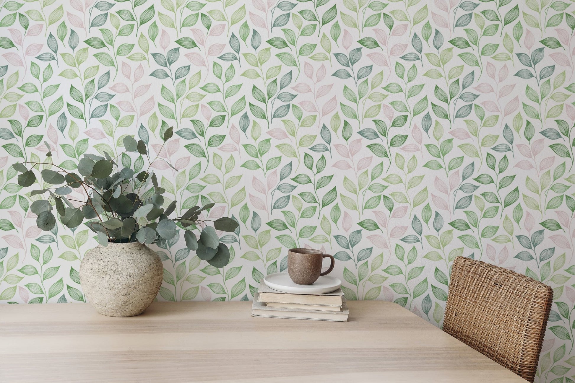 Wallpaper with a repeat leaf design behind a light wood dining table and vase.