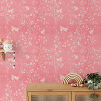 Magnolia tree and birds wallpaper behind a wooden console table with decor.