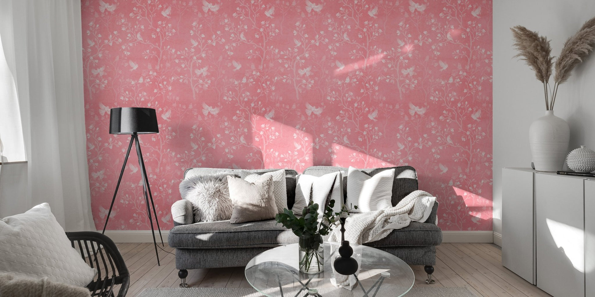 Living room setting with pink chinoiserie wallpaper and a grey sofa.
