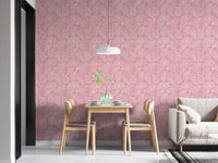 Pink hand drawn paisley wallpaper in a dining space with light wood chairs.