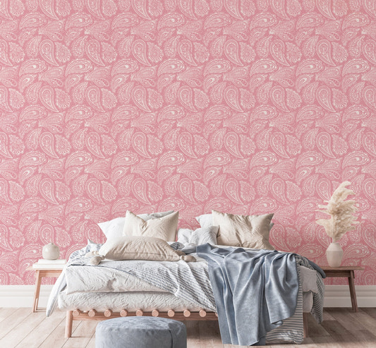Pink paisley wallpaper behind a bed with white and blue linens.