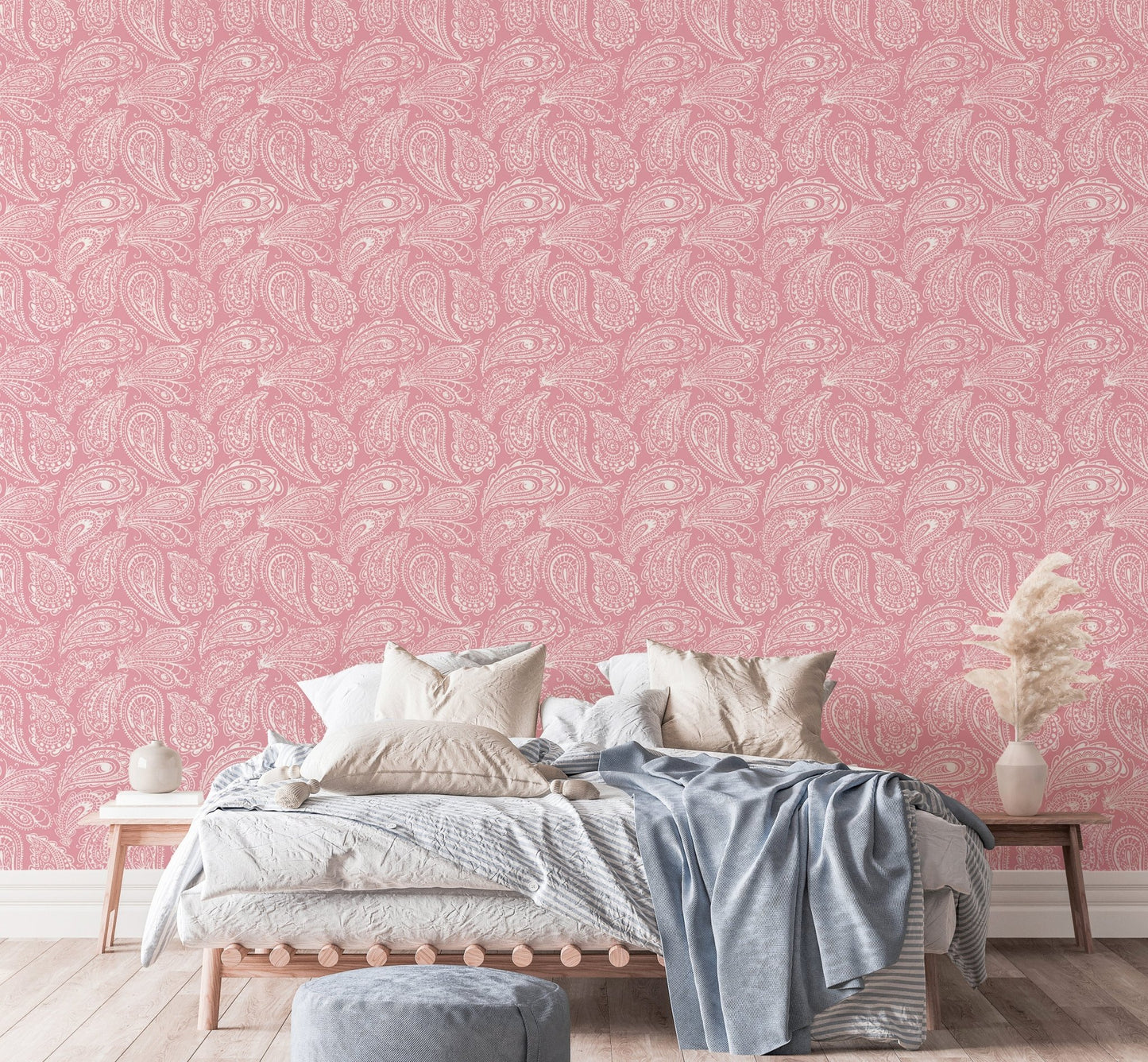 Pink paisley wallpaper behind a bed with white and blue linens.