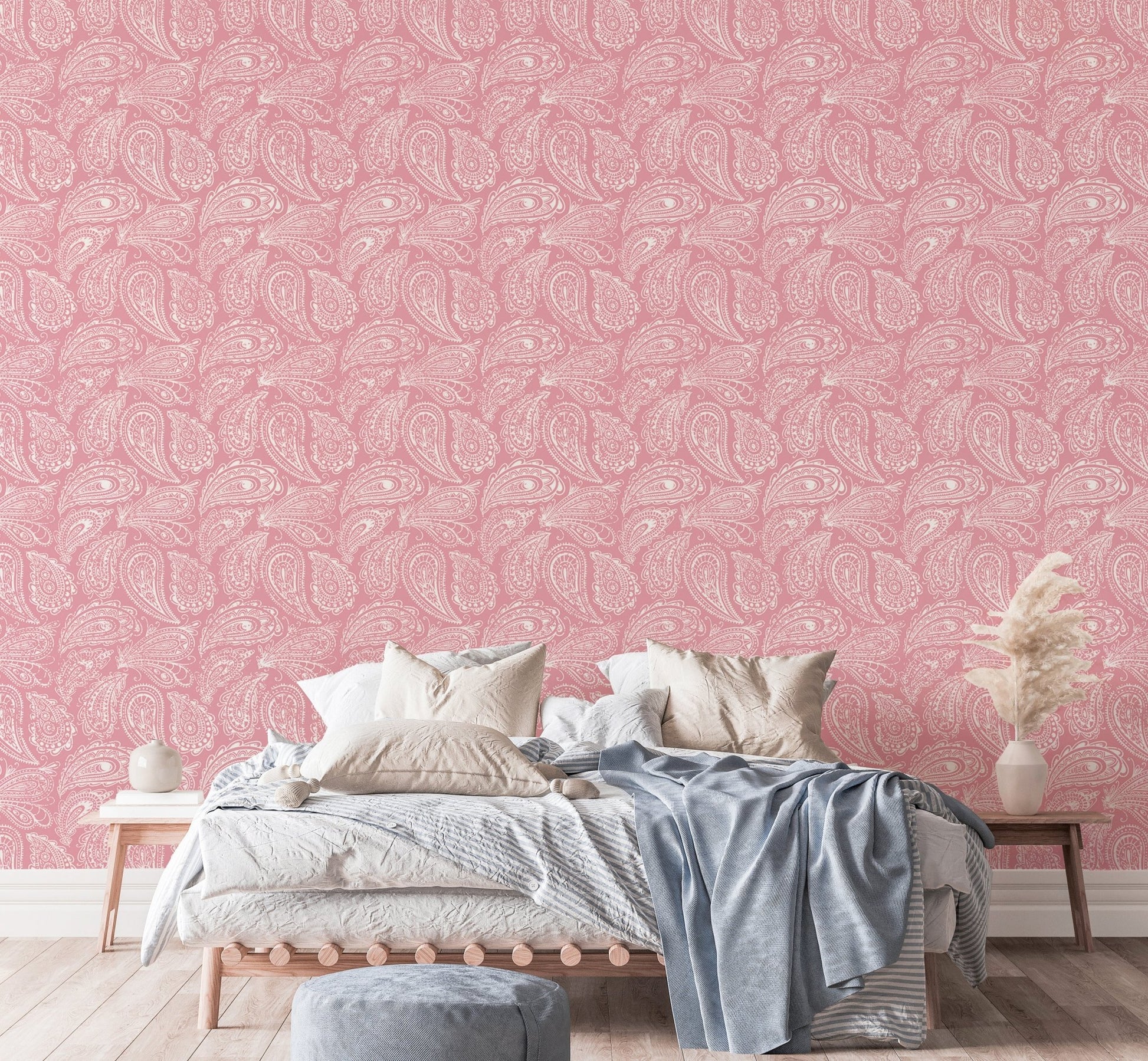 Pink paisley wallpaper behind a bed with white and blue linens.