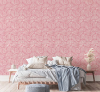 Pink paisley wallpaper behind a bed with white and blue linens.