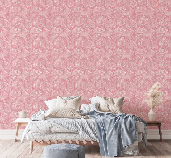 Pink paisley wallpaper behind a bed with white and blue linens.