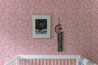 Decorative pink ornament wallpaper in a nursery with a framed mountain print.