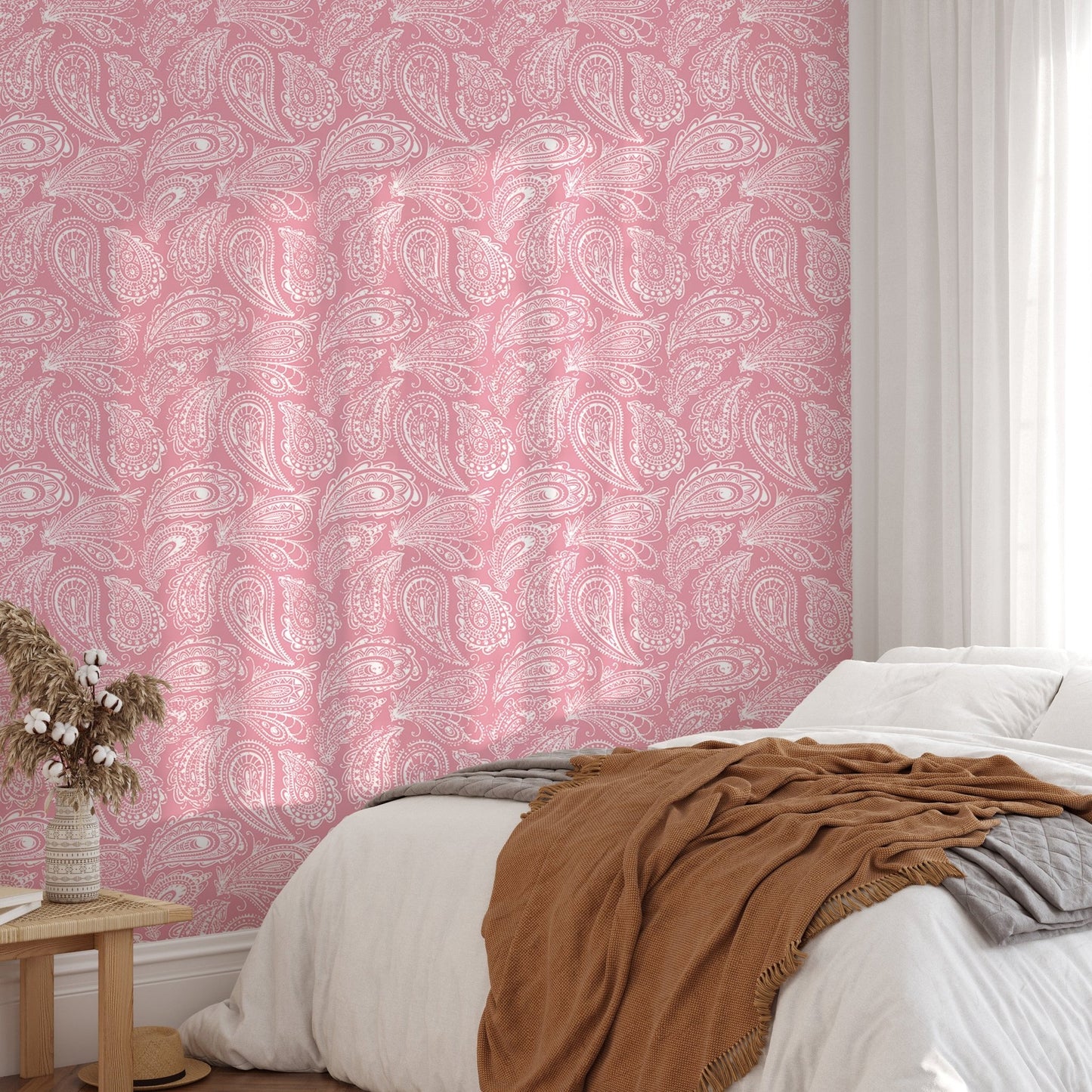 Pink hand drawn paisley wallpaper in a bedroom with a white bed and brown throw.