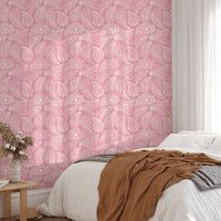 Pink hand drawn paisley wallpaper in a bedroom with a white bed and brown throw.