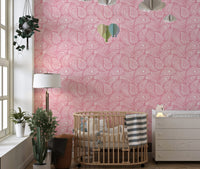 Nursery wall featuring pink hand drawn ornament wallpaper and a wood crib.