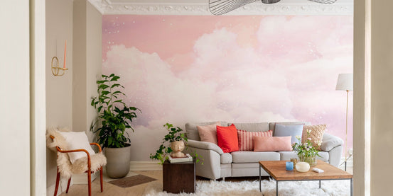 Pink pastel cloud wall mural in a modern living room with a grey sofa.