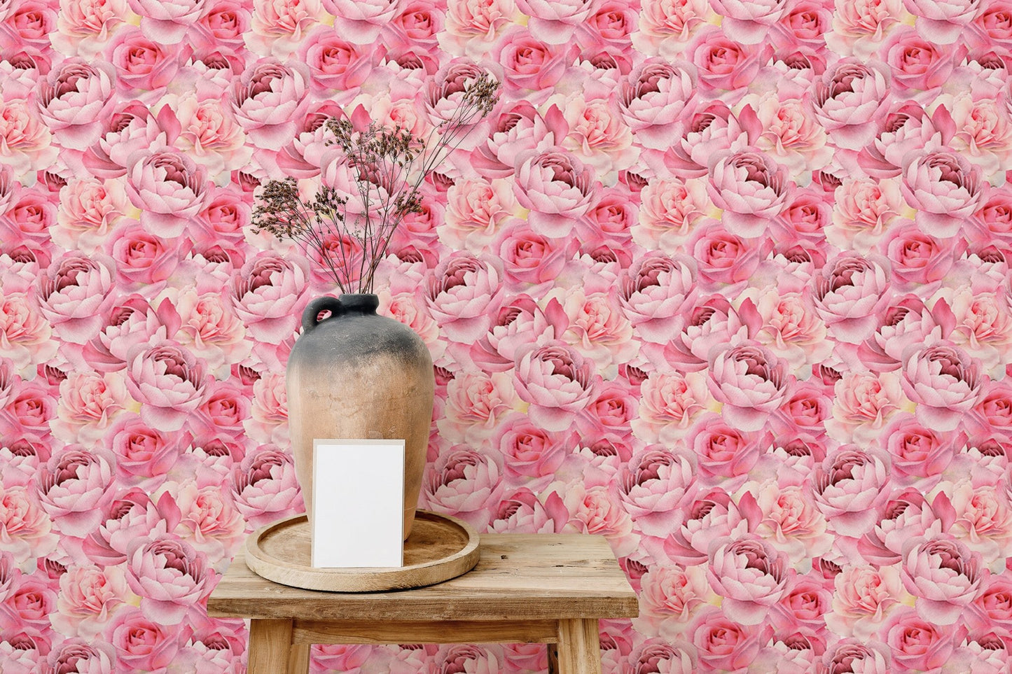 Pink peonies roses wallpaper behind wooden stool with dry plants in vase.