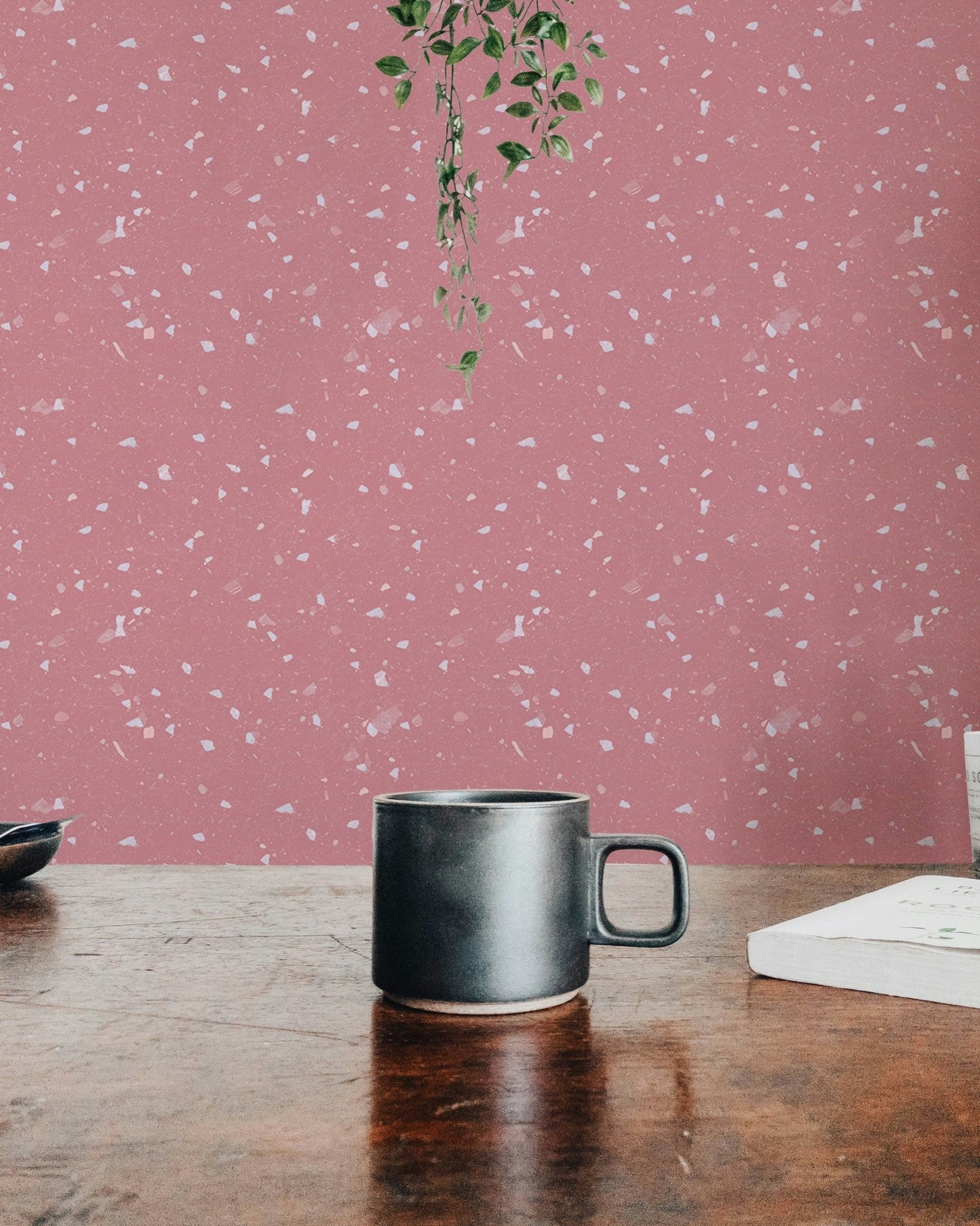 Work desk with coffee mug against a pink terrazzo wallpaper background.