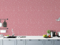 Kitchen backsplash area with pink terrazzo wallpaper and white cabinets.