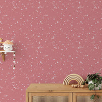 Children's room featuring pink stone pattern wallpaper and wooden furniture.
