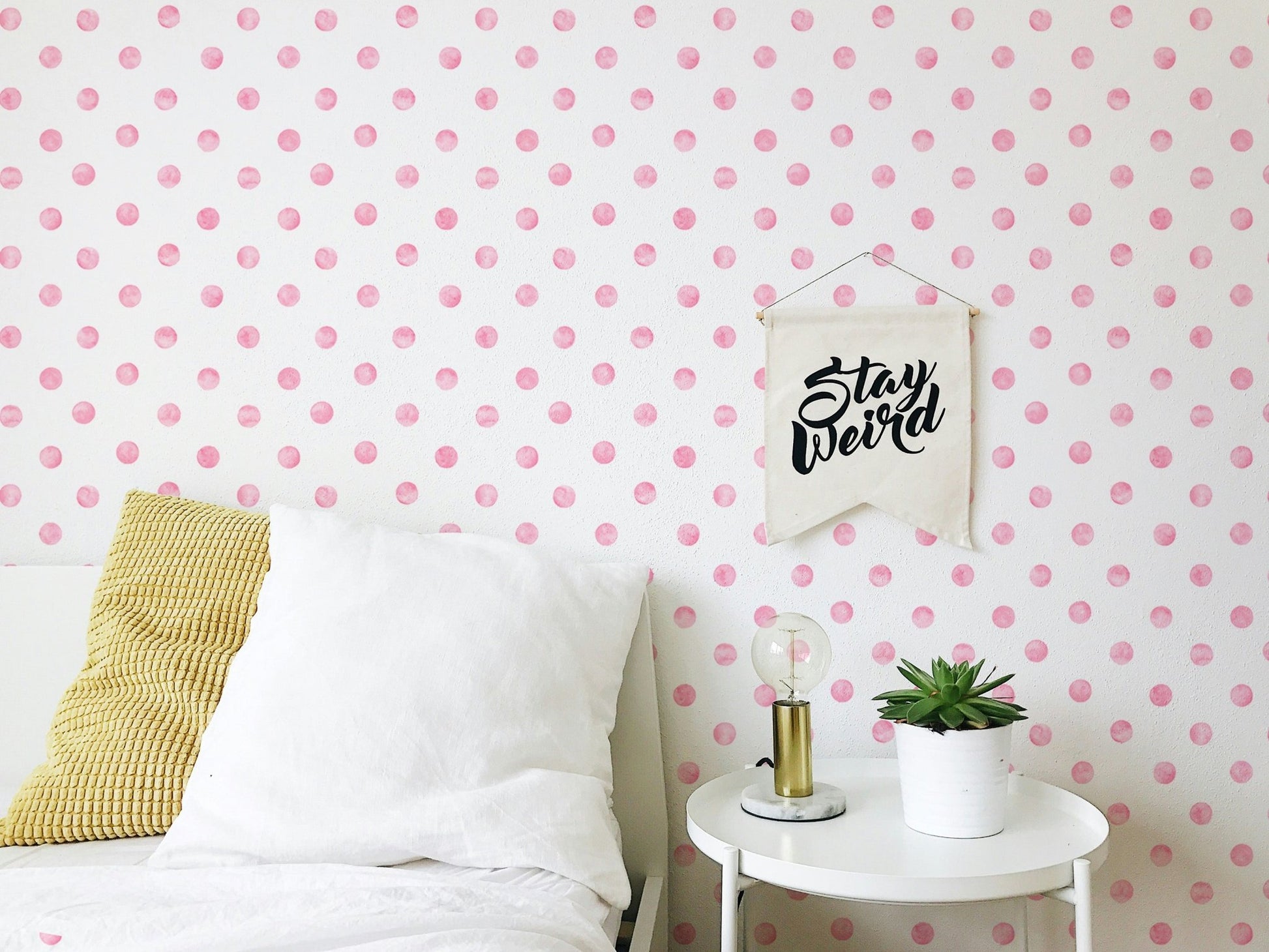 Bedroom wallpaper featuring pink spots behind a white bed and side table.