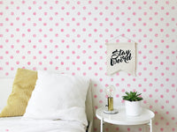 Bedroom wallpaper featuring pink spots behind a white bed and side table.