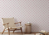Neutral reading area with pink polka dot wallpaper and a wooden lounge chair.